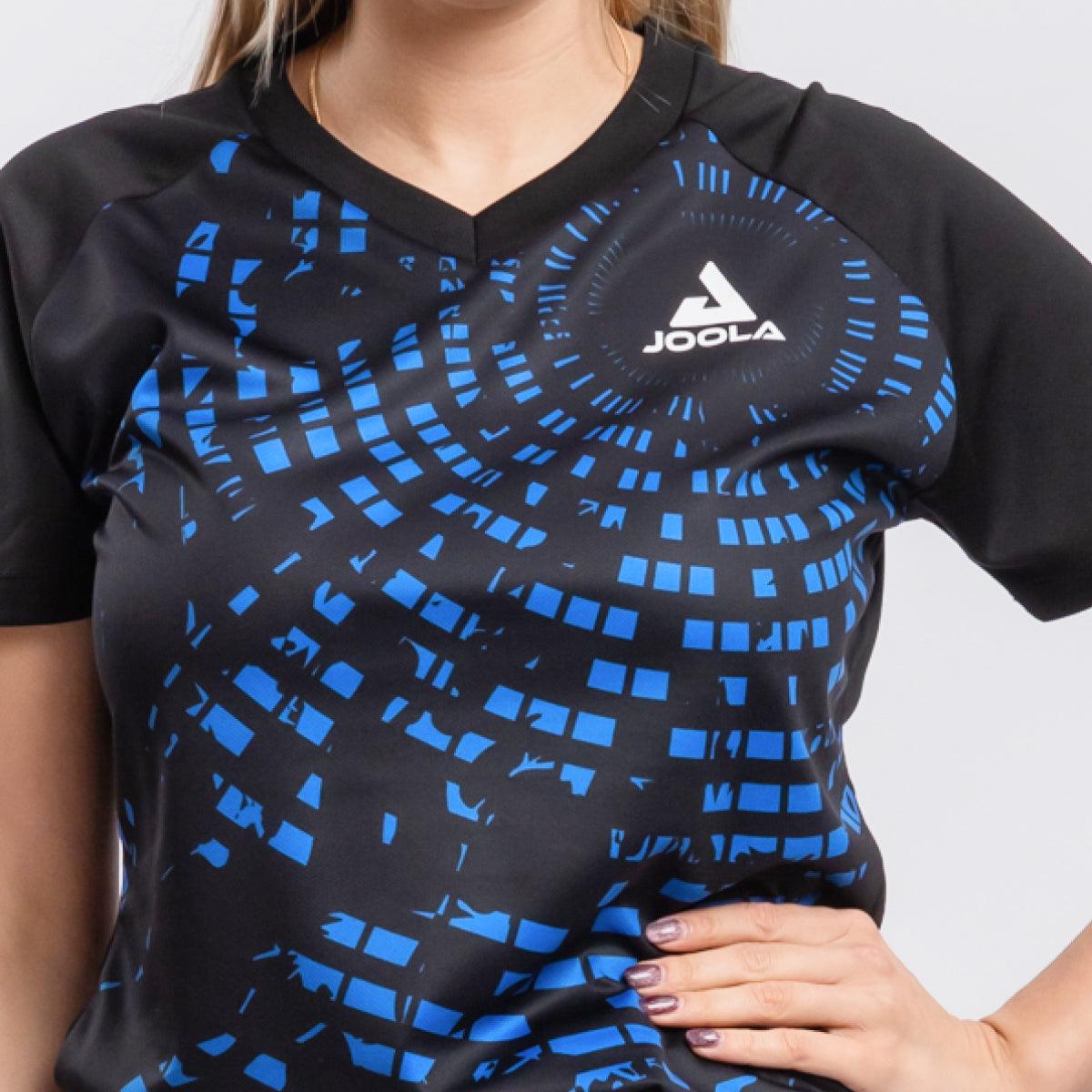 Schwarzes JOOLA Sportshirt mit blauem geometrischem Muster, V-Ausschnitt, getragen von einer Frau.