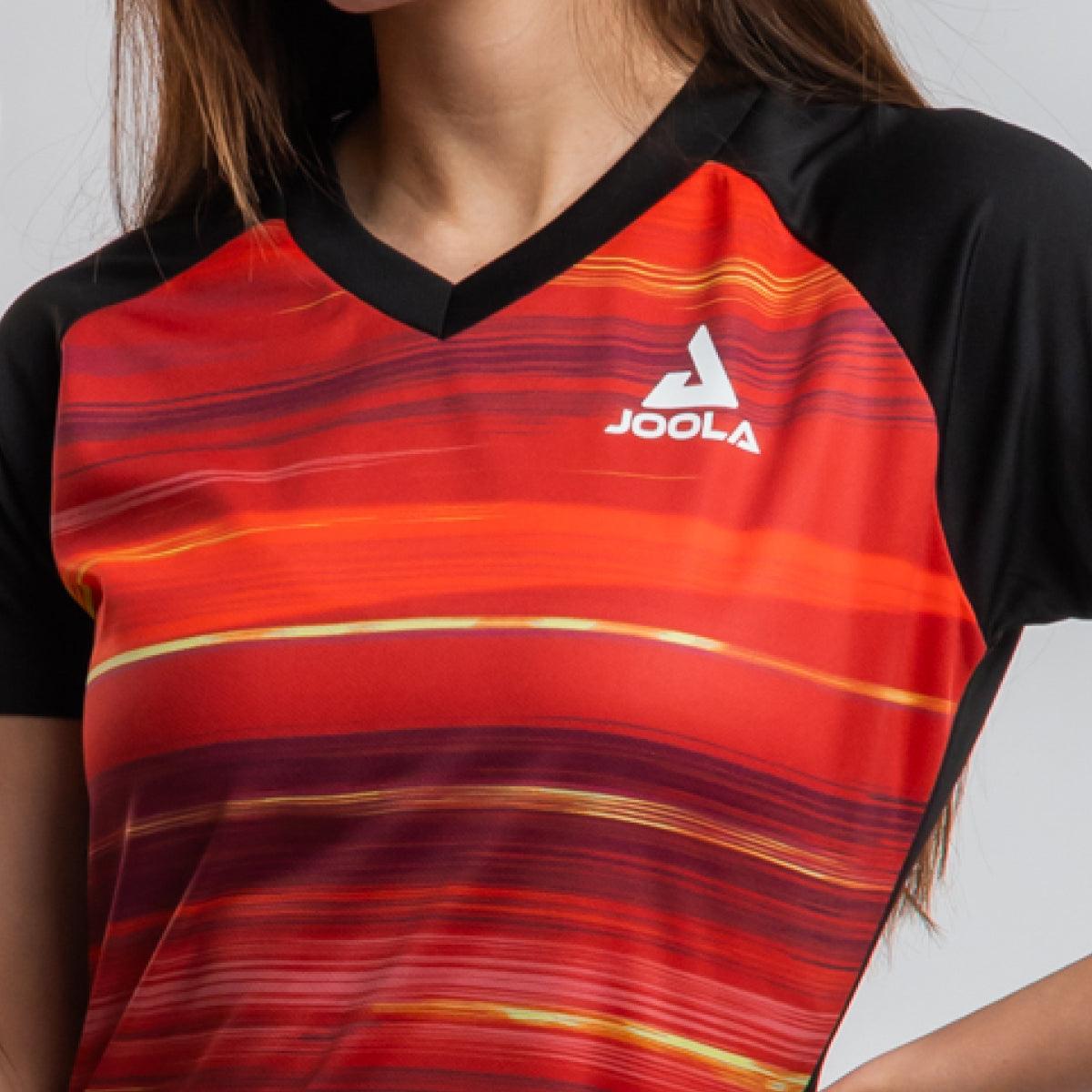 Frau trägt ein rotes und schwarzes JOOLA Sportshirt mit V-Ausschnitt.